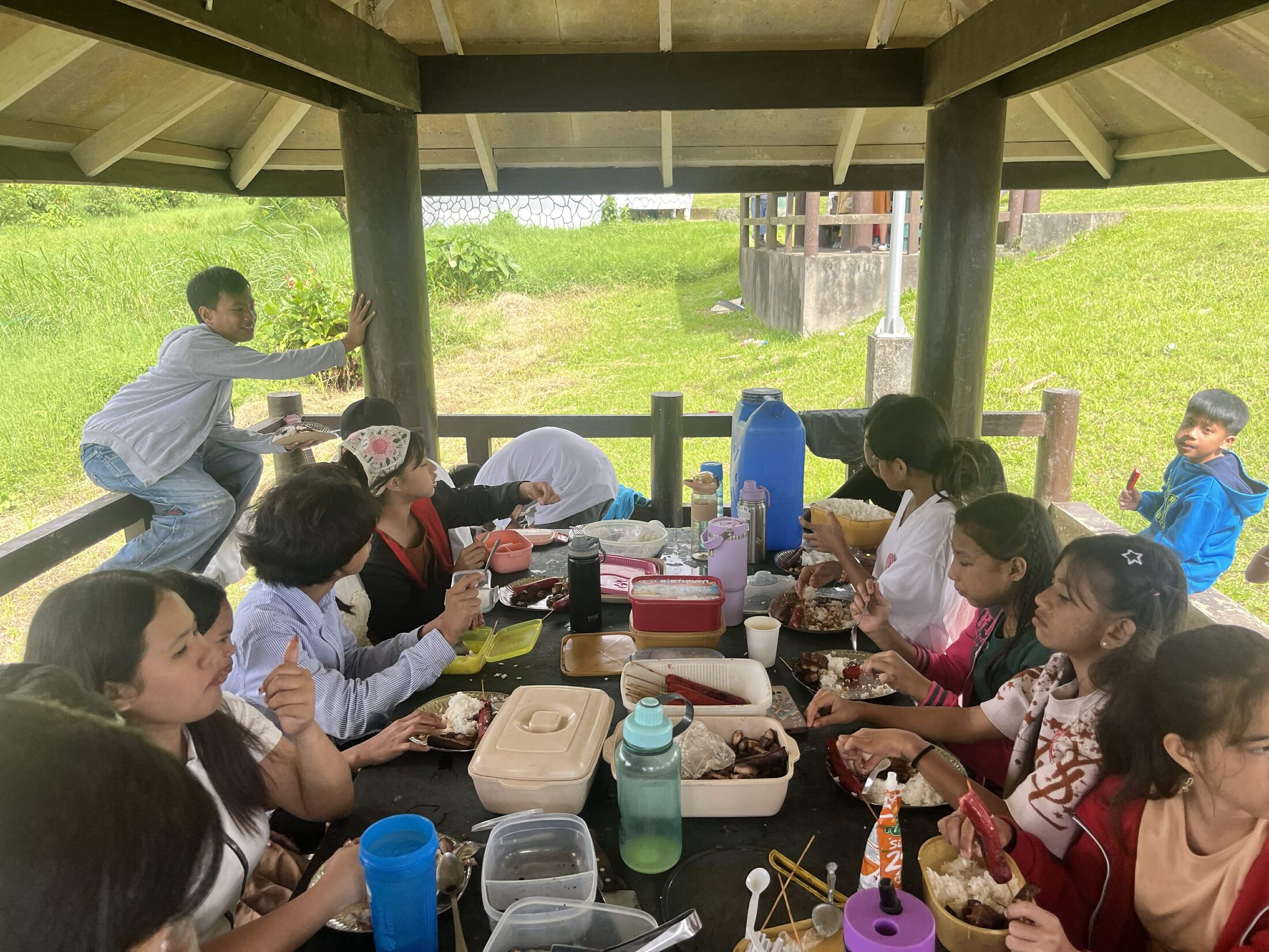 Young people sharing a meal together at an outdoor shelter